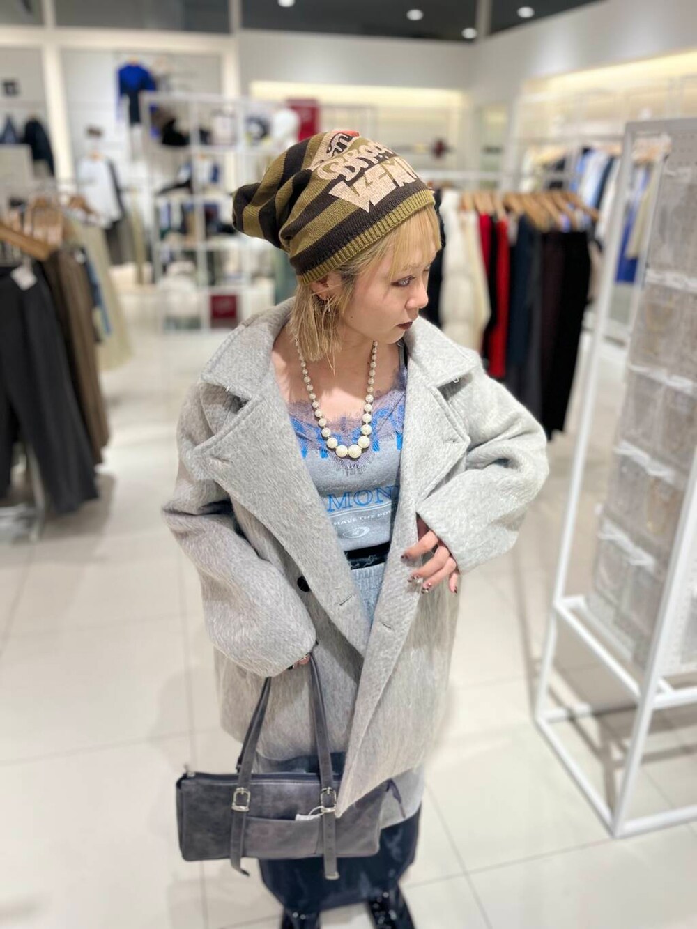 ブラック系のブーツ、ブラック系のスカート、グレー系のボストンバッグを着用したレディースの秋コーディネートの5枚目の写真