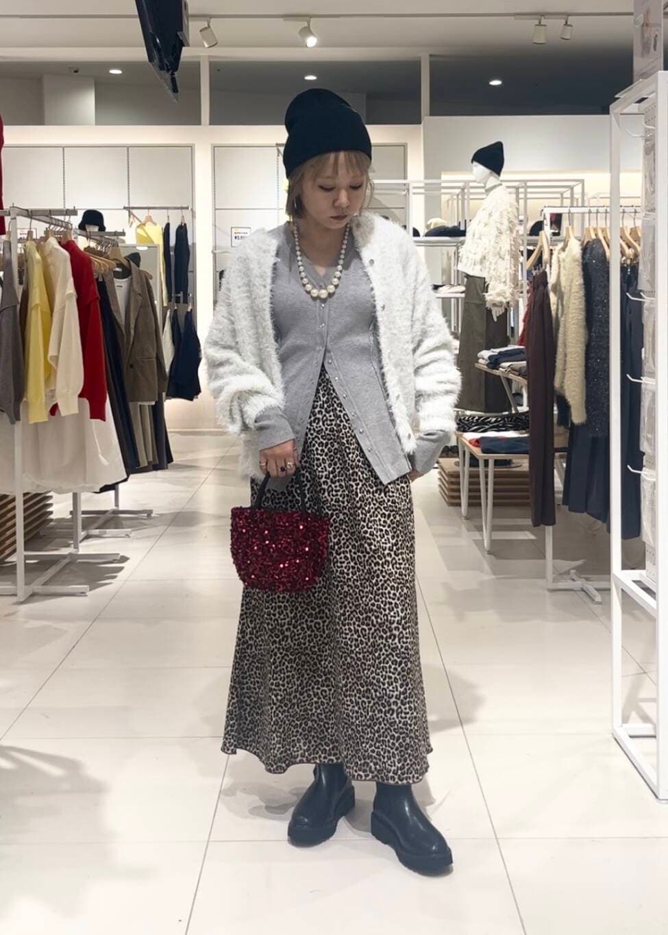 ブラック系のブーツ、ホワイト系のニット/セーター、グレー系のカーディガン/ボレロを着用したレディースの秋コーディネートの2枚目の写真