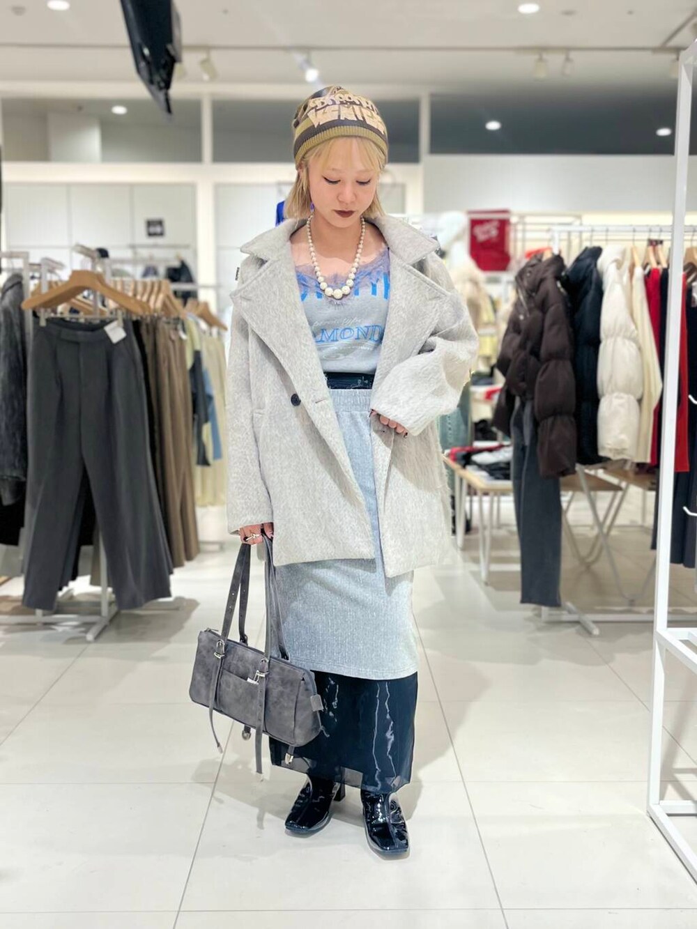 ブラック系のブーツ、ブラック系のスカート、グレー系のボストンバッグを着用したレディースの秋コーディネートの2枚目の写真