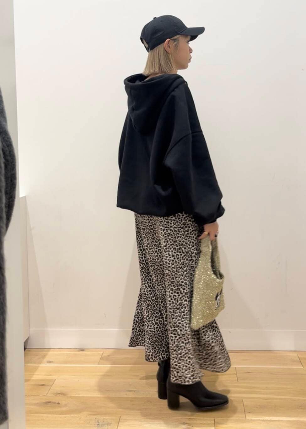 ブラック系のブーツ、ゴールド系のトートバッグ、ブラウン系のスカートを着用したレディースの秋コーディネートの3枚目の写真