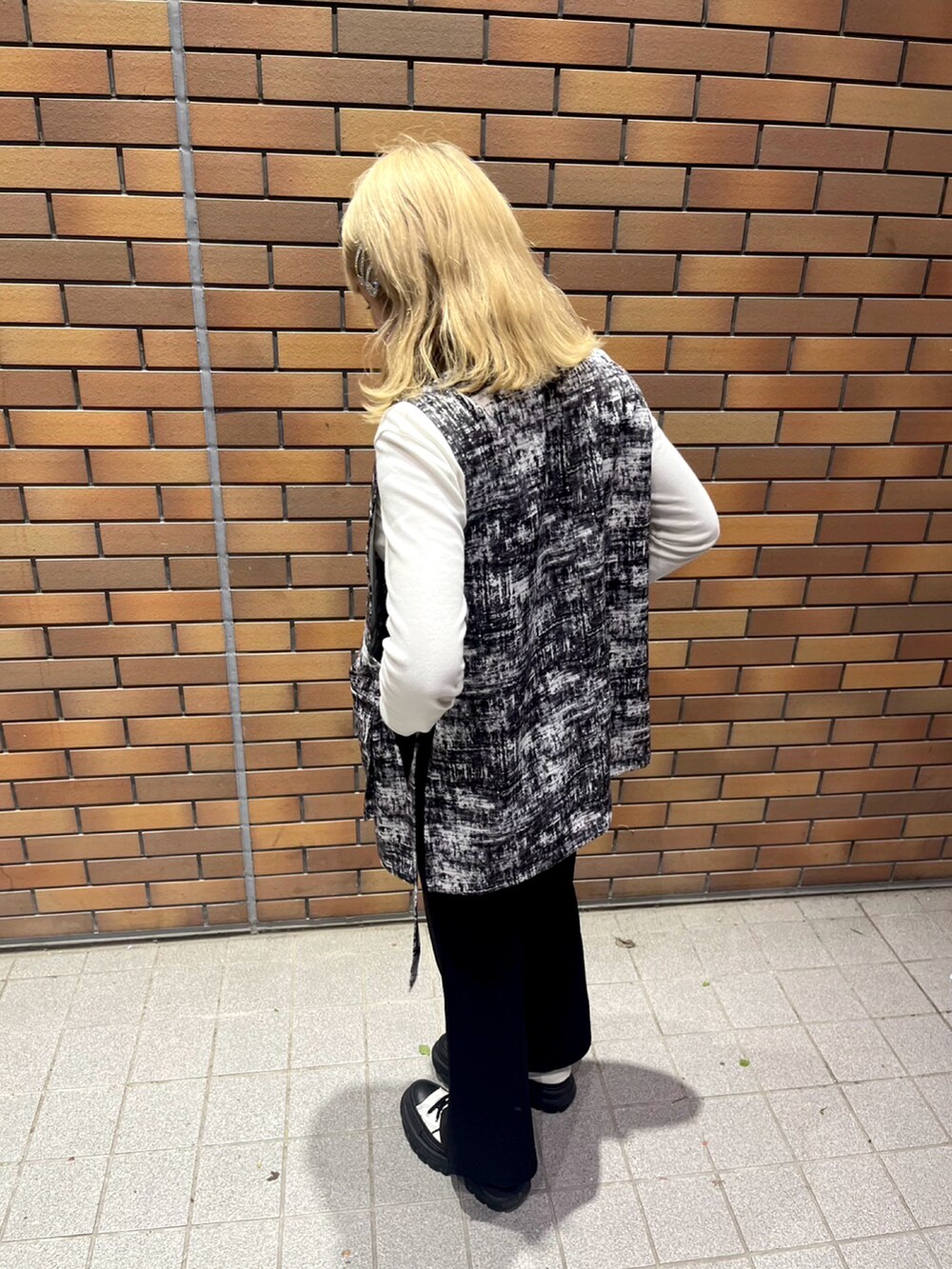 グレー系のベスト、ホワイト系のTシャツ/カットソー、ブラック系のパンツを着用したレディースの春コーディネートの2枚目の写真