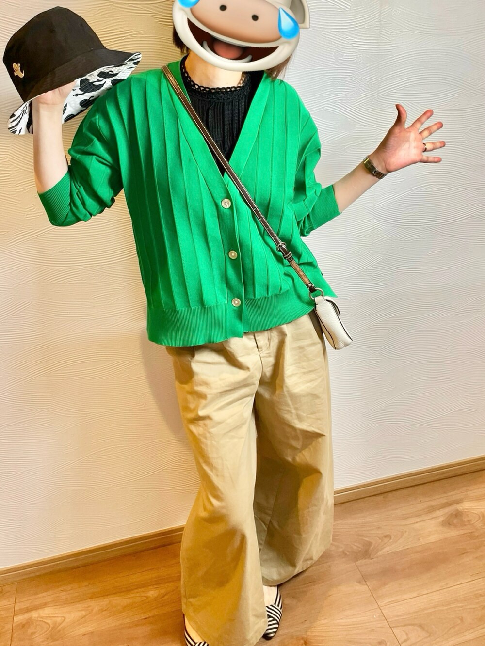 グリーン系のカーディガン/ボレロ、ベージュ系のチノパンツ、ブラック系のハットを着用したレディースの春コーディネートの2枚目の写真