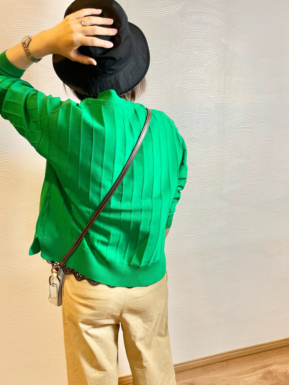 グリーン系のカーディガン/ボレロ、ベージュ系のチノパンツ、ブラック系のハットを着用したレディースの春コーディネートの5枚目の写真