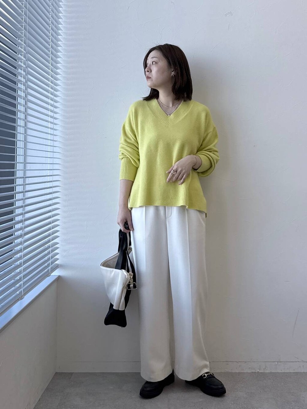 ベージュ系のトートバッグ、ホワイト系のその他パンツ、イエロー系のニット/セーターを着用したレディースの冬コーディネートの2枚目の写真