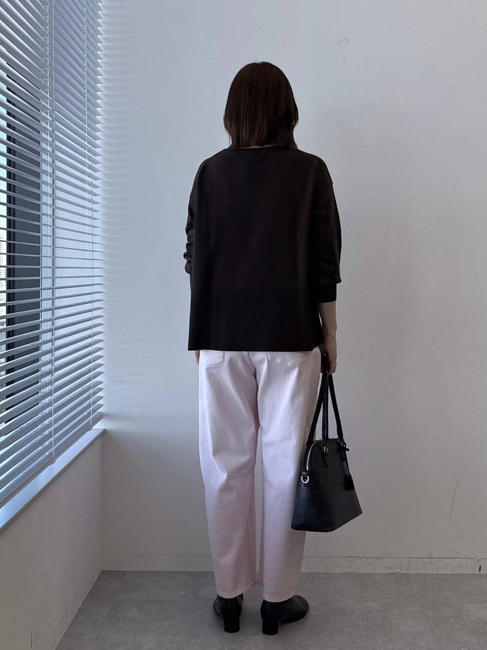 ブラウン系のニット/セーター、ブラック系のブーツ、ピンク系のデニムパンツを着用したレディースの冬コーディネートの4枚目の写真