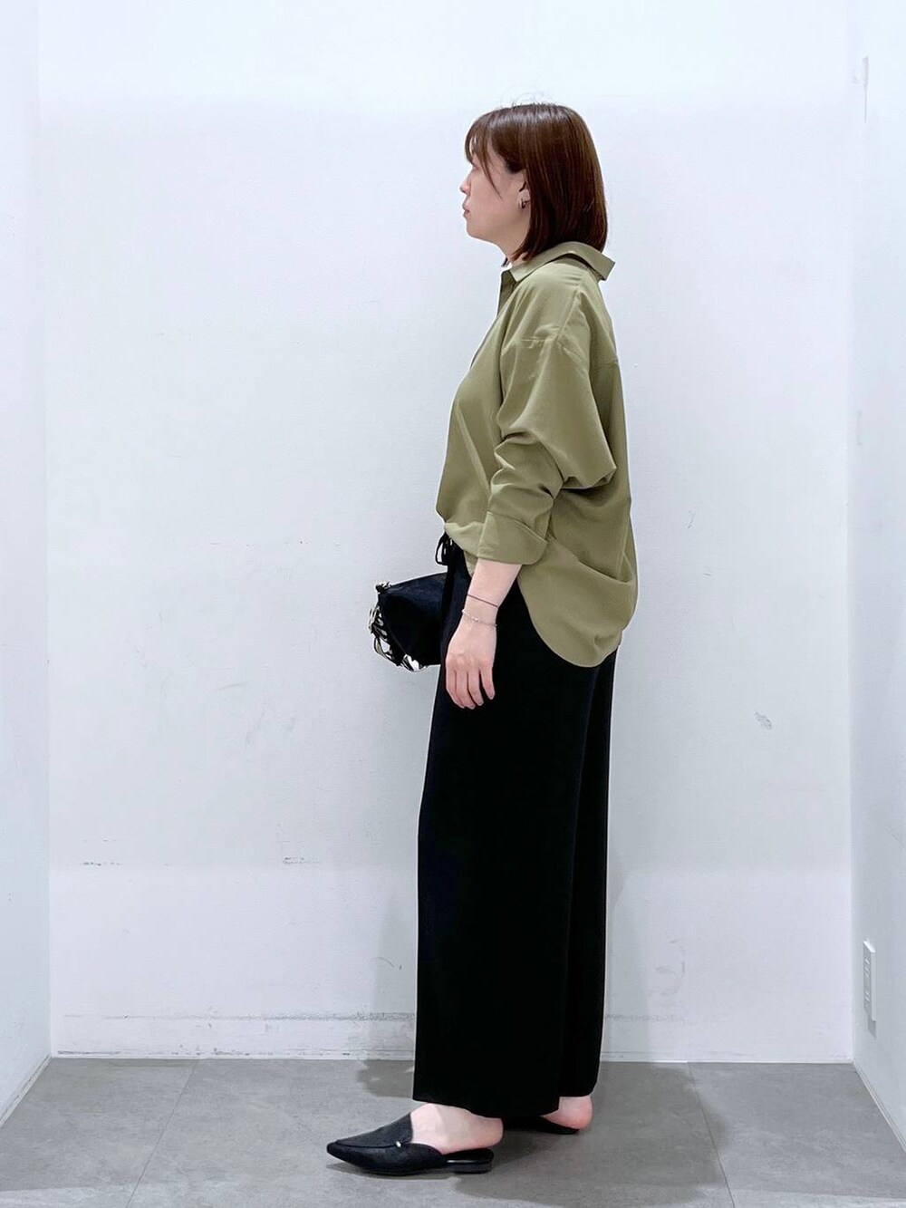 ブラック系のその他パンツ、グリーン系のシャツ/ブラウス、ブラック系のパンプスを着用したレディースの春コーディネートの2枚目の写真