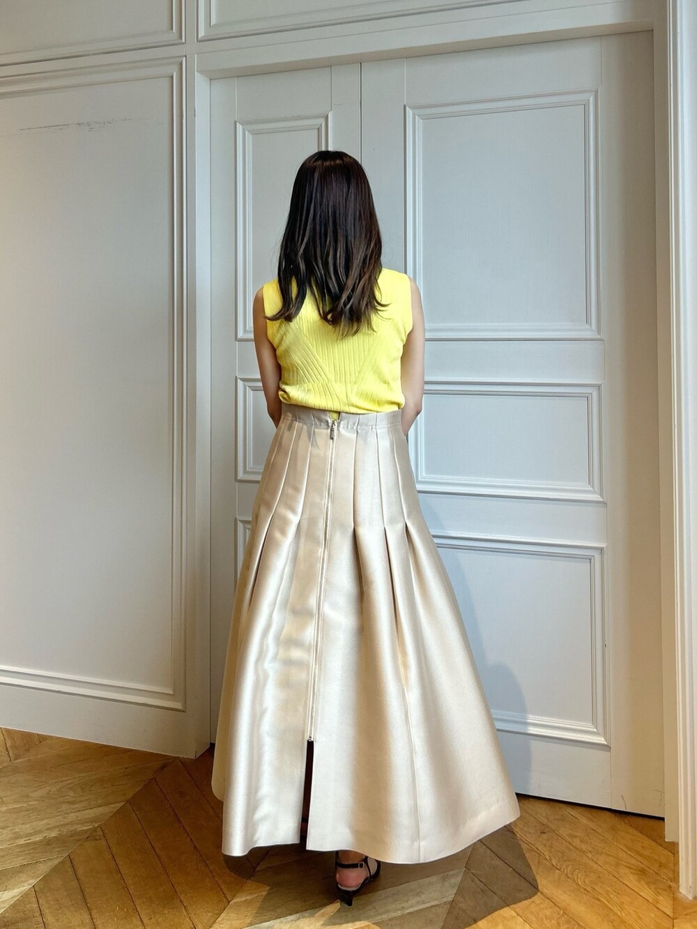 イエロー系のニット/セーター、ベージュ系のスカートを着用したレディースの春コーディネートの3枚目の写真