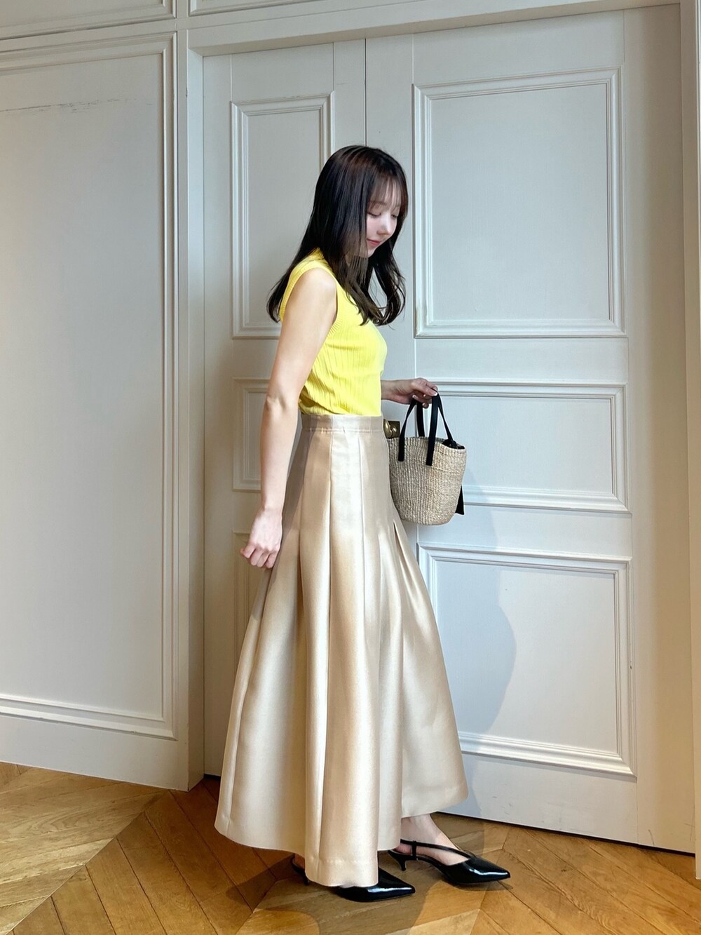 イエロー系のニット/セーター、ベージュ系のスカートを着用したレディースの春コーディネートの2枚目の写真