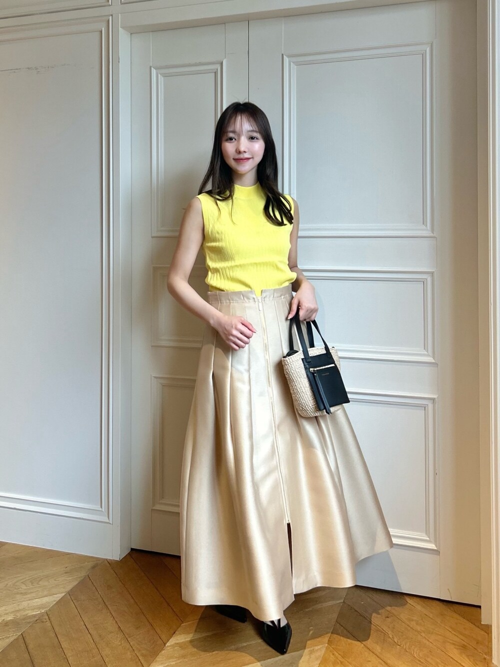 イエロー系のニット/セーター、ベージュ系のスカートを着用したレディースの春コーディネートの6枚目の写真