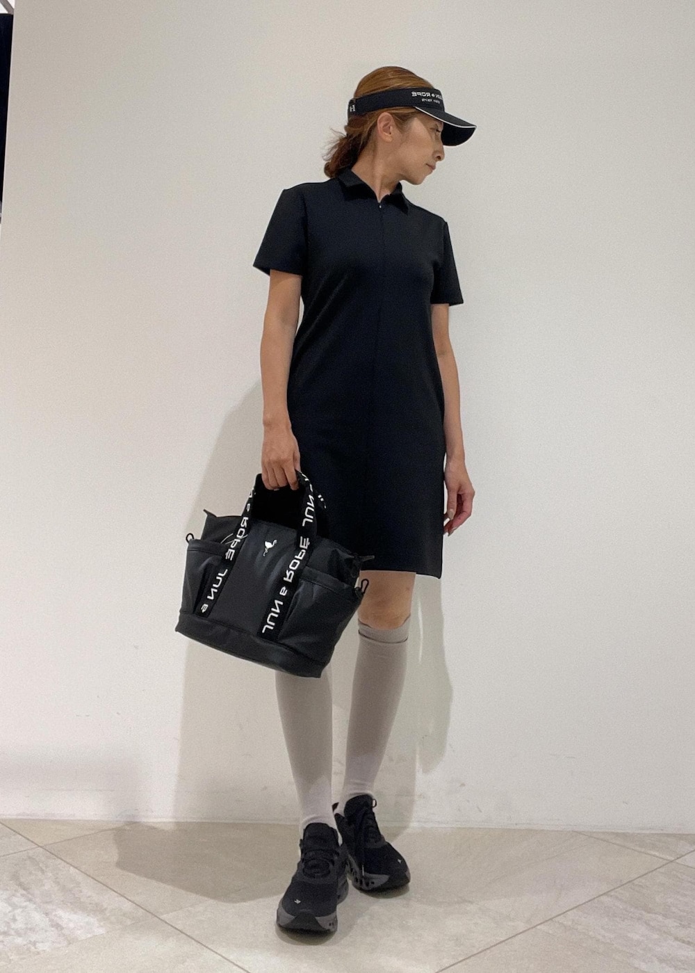 ブラック系のハンドバッグ、ブラック系のワンピース、ブラック系のサンバイザーを着用したレディースの秋コーディネートの4枚目の写真