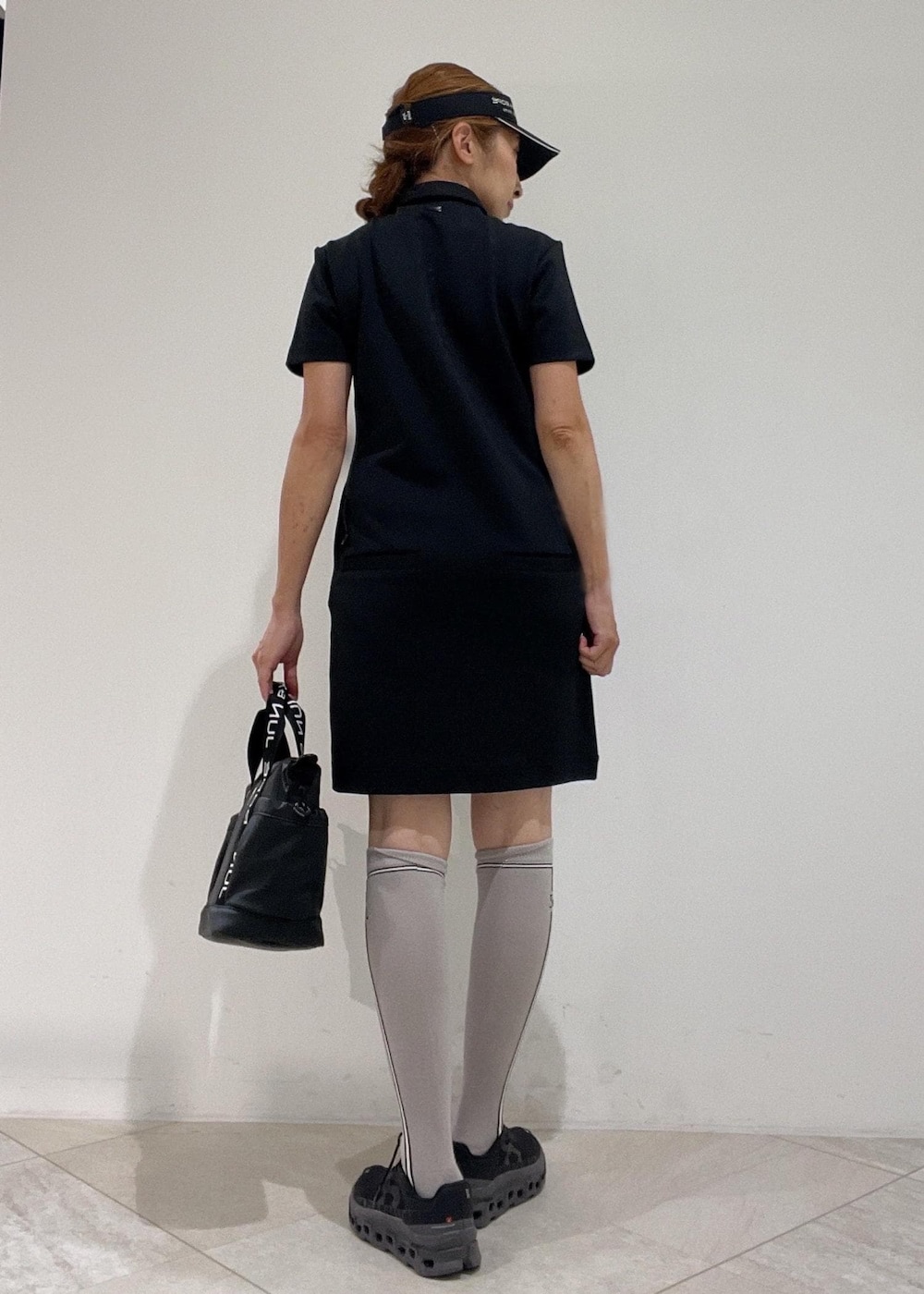 ブラック系のハンドバッグ、ブラック系のワンピース、ブラック系のサンバイザーを着用したレディースの秋コーディネートの3枚目の写真