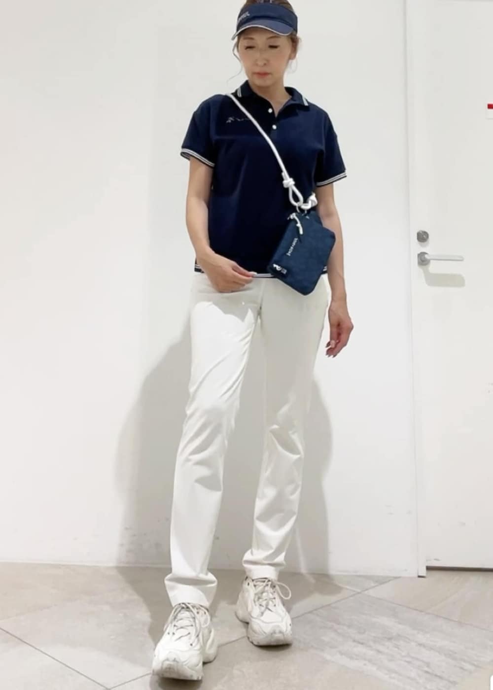 ブルー系のショルダーバッグ、ブルー系のポロシャツ、ホワイト系のその他パンツを着用したレディースの春コーディネートの3枚目の写真