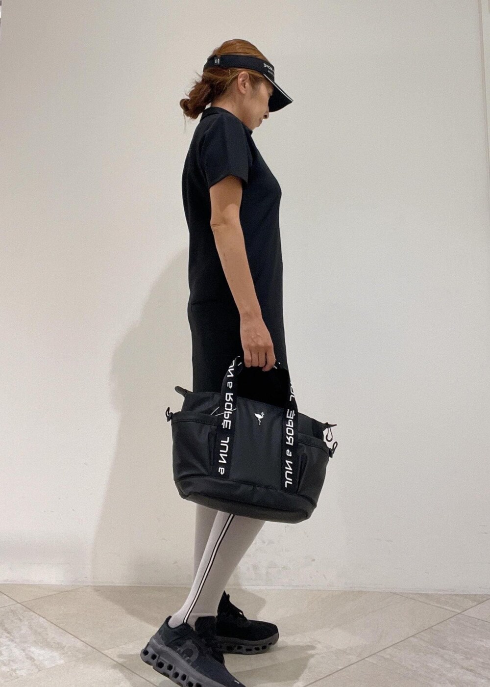 ブラック系のハンドバッグ、ブラック系のワンピース、ブラック系のサンバイザーを着用したレディースの秋コーディネートの2枚目の写真