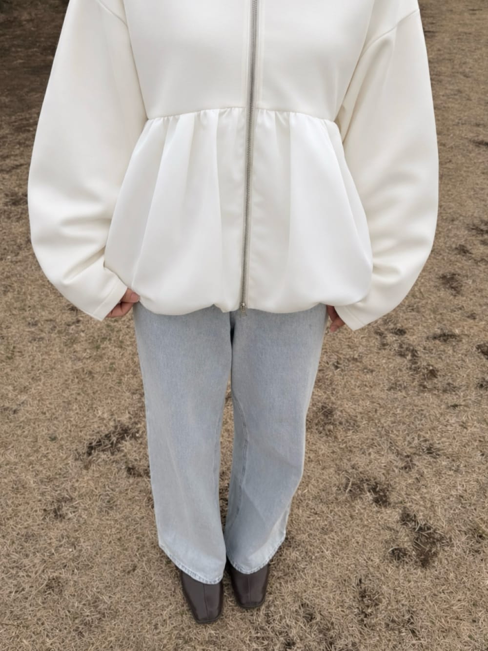 ブルー系のデニムパンツ、ブラウン系のパンプス、ベージュ系のパーカーを着用したレディースの冬コーディネートの2枚目の写真