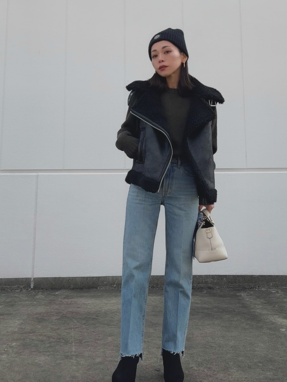 ブラック系のジャケット/アウター、グリーン系のニット/セーター、ホワイト系のバッグを着用したレディースの冬コーディネートの2枚目の写真