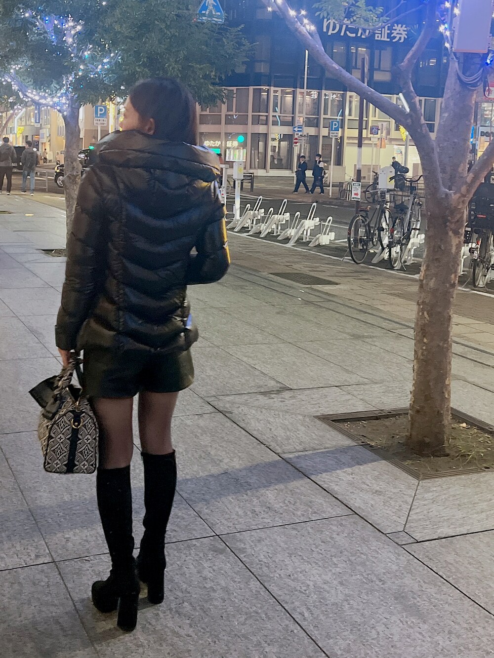 ブラック系のダウンジャケット/コート、ブラック系のハンドバッグ、ブラック系のブーツを着用したレディースの冬コーディネートの2枚目の写真