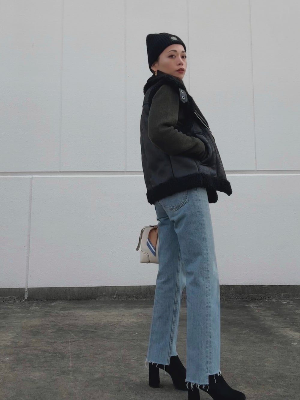 ブラック系のジャケット/アウター、グリーン系のニット/セーター、ホワイト系のバッグを着用したレディースの冬コーディネートの3枚目の写真