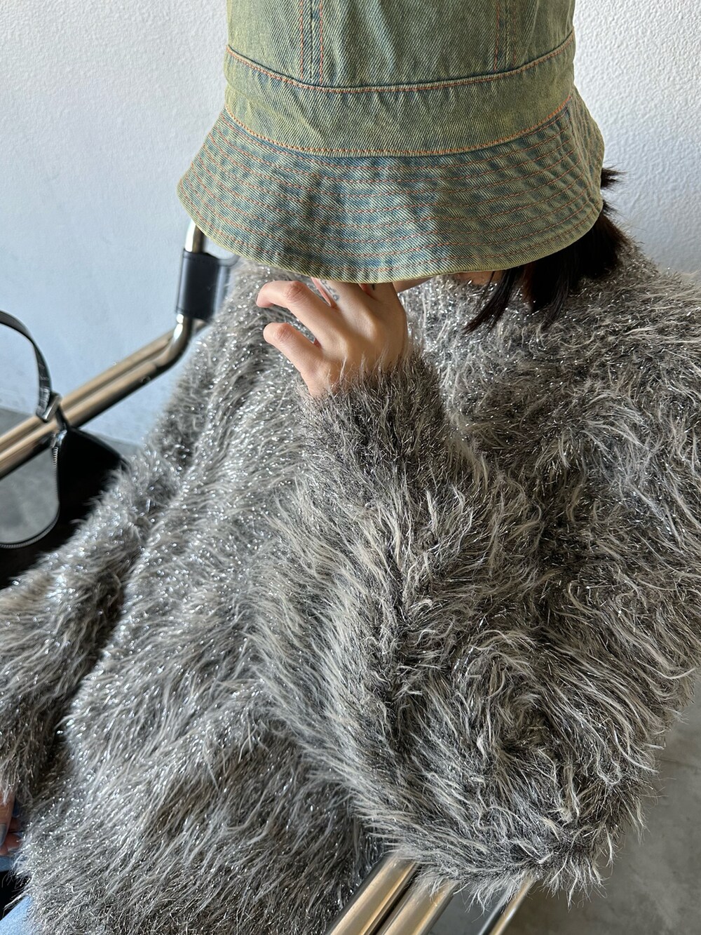 ブルー系のデニムパンツ、ベージュ系のブーツ、シルバー系のニット/セーターを着用したレディースの冬コーディネートの2枚目の写真