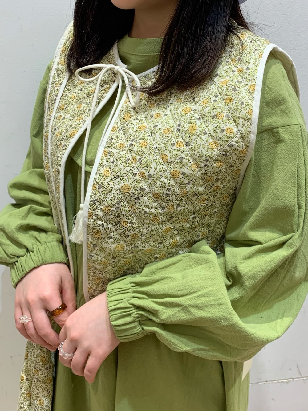 グリーン系のワンピース、ホワイト系のベスト、ホワイト系のバッグを着用したレディースの冬コーディネートの2枚目の写真