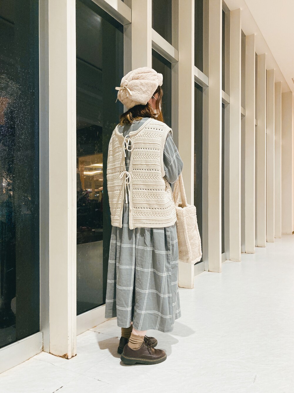 ホワイト系のトートバッグ、ベージュ系のベスト、グレー系のワンピース/ドレスを着用したレディースの秋コーディネートの2枚目の写真