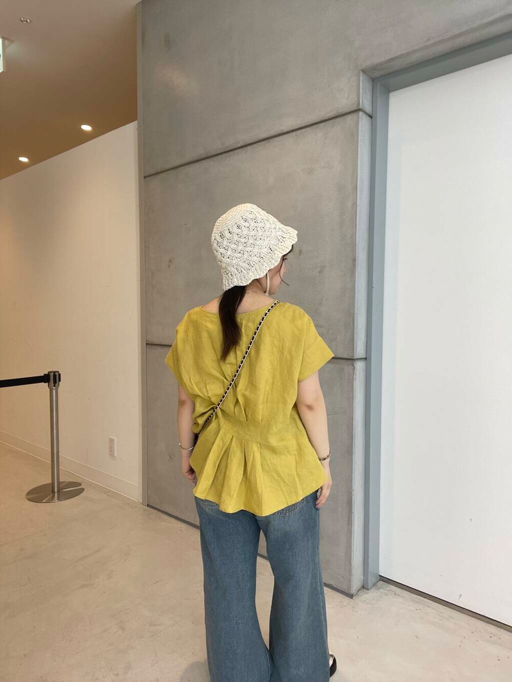 ブルー系のデニムパンツ、ホワイト系のサンダル、ブラウン系のショルダーバッグを着用したレディースの夏コーディネートの6枚目の写真