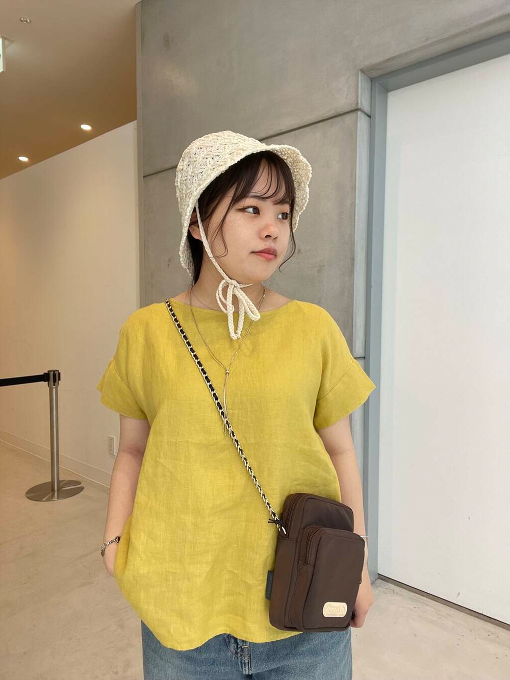 ブルー系のデニムパンツ、ホワイト系のサンダル、ブラウン系のショルダーバッグを着用したレディースの夏コーディネートの5枚目の写真