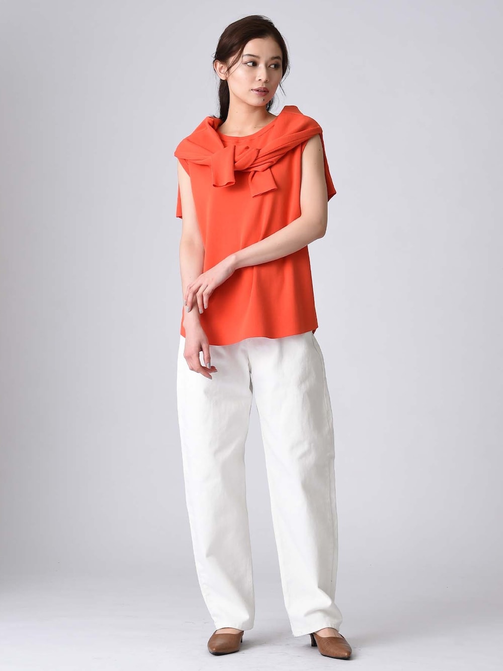 オレンジ系のアンサンブルを着用したレディースの春コーディネートの2枚目の写真