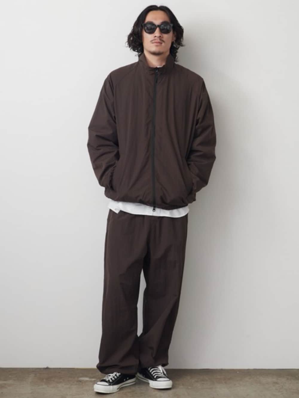 ホワイト系のTシャツ/カットソー、ブラック系のスニーカー、ブラウン系のブルゾンを着用したメンズの秋コーディネートの2枚目の写真