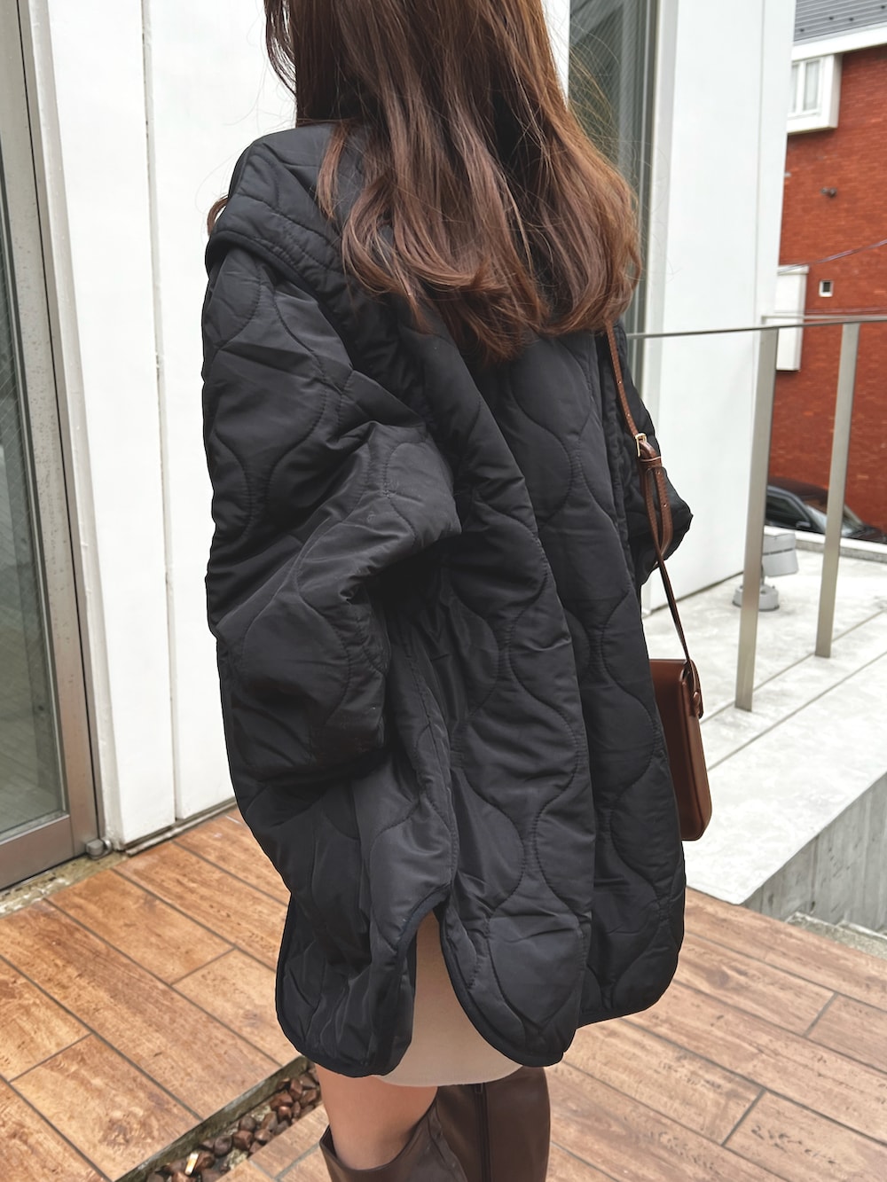 ブラック系のノーカラージャケット、ブラウン系のブーツ、ベージュ系のスカートを着用したレディースの冬コーディネートの2枚目の写真