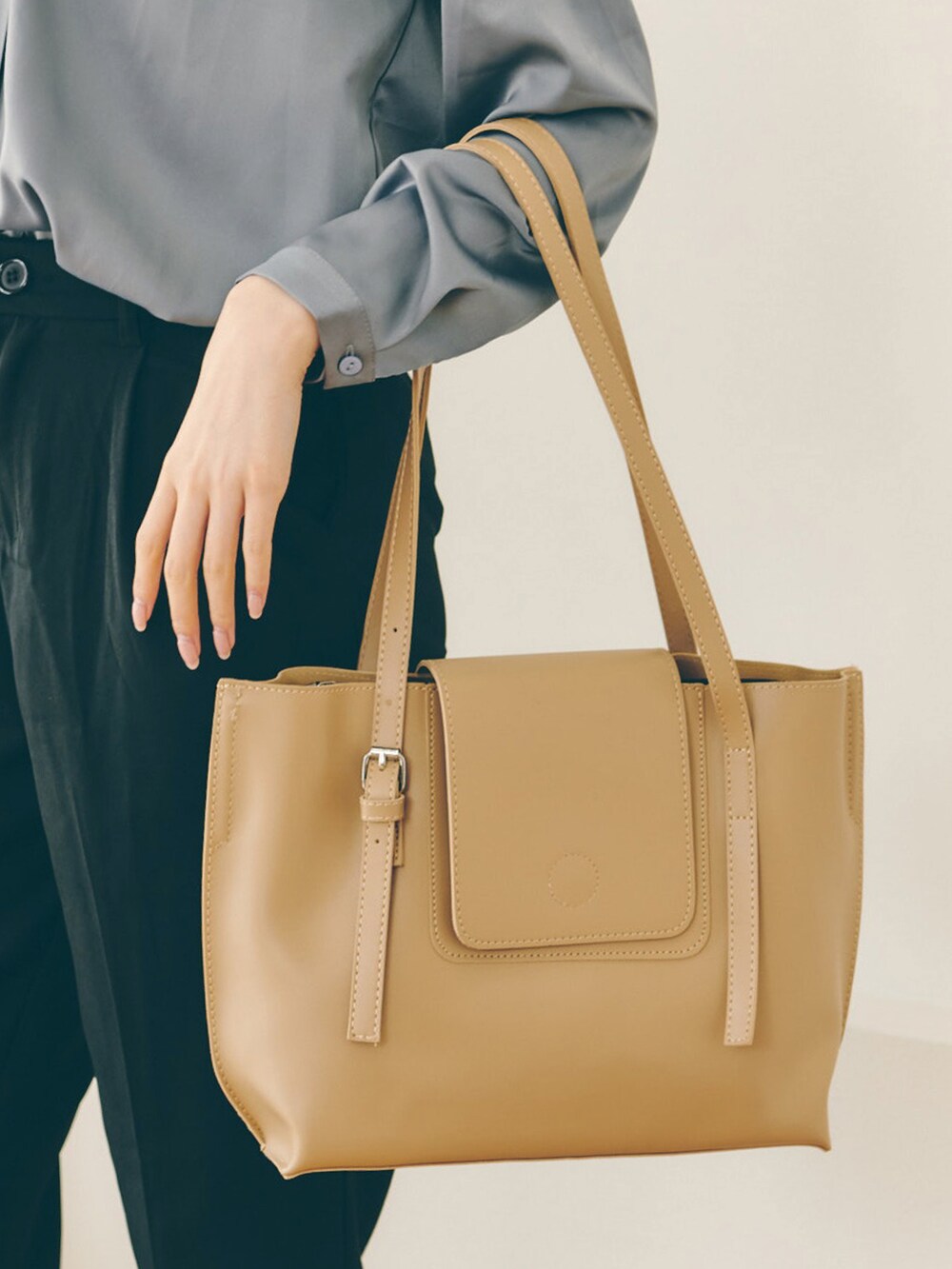 ブラウン系のトートバッグ、ベージュ系のシャツ/ブラウス、ブラック系のスラックスを着用したレディースの春コーディネートの2枚目の写真