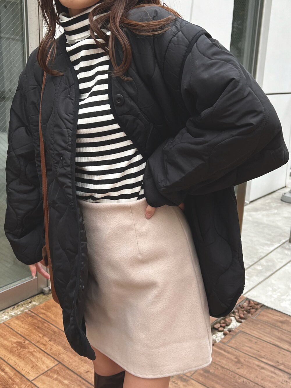 ブラック系のノーカラージャケット、ブラウン系のブーツ、ベージュ系のスカートを着用したレディースの冬コーディネートの3枚目の写真