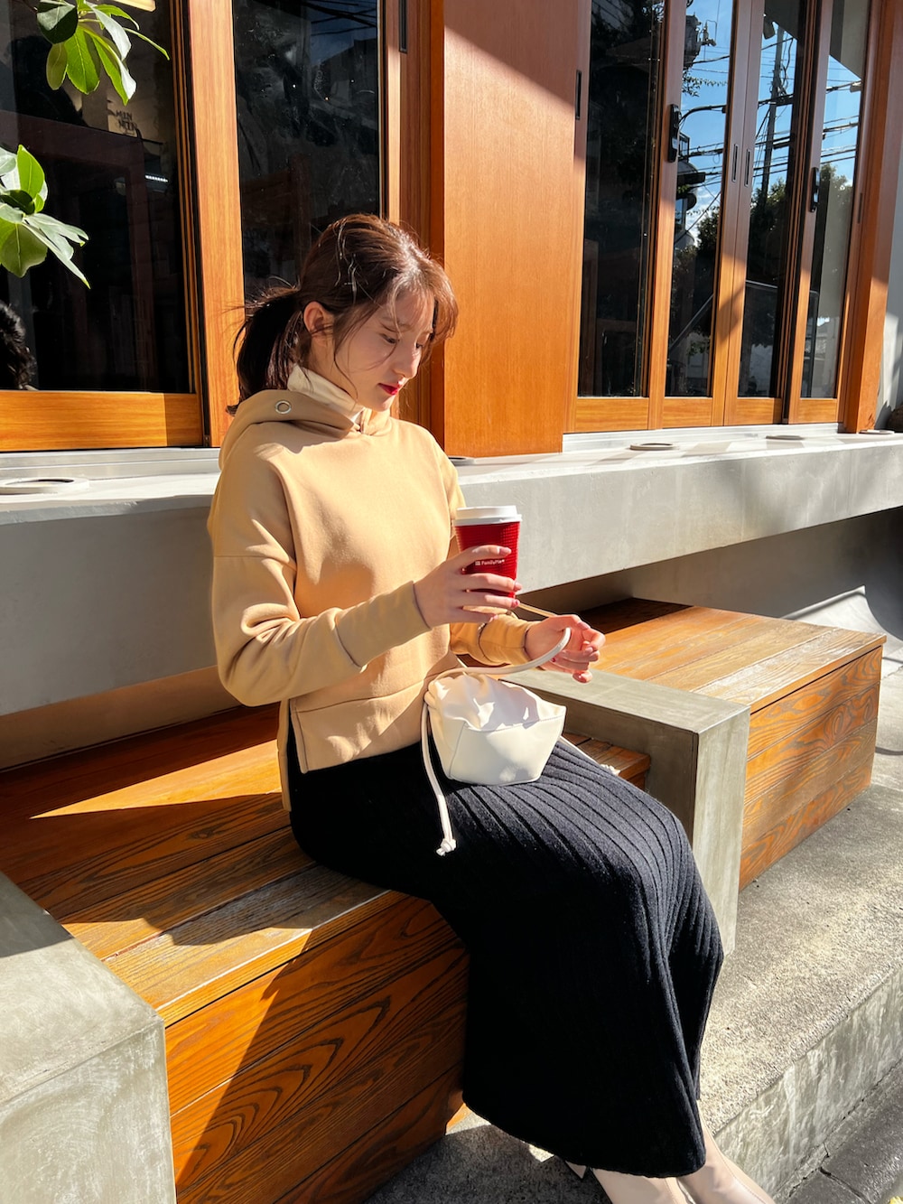 ブラウン系のパーカー、ブラック系のスカート、ベージュ系のブーツを着用したレディースの秋コーディネートの2枚目の写真