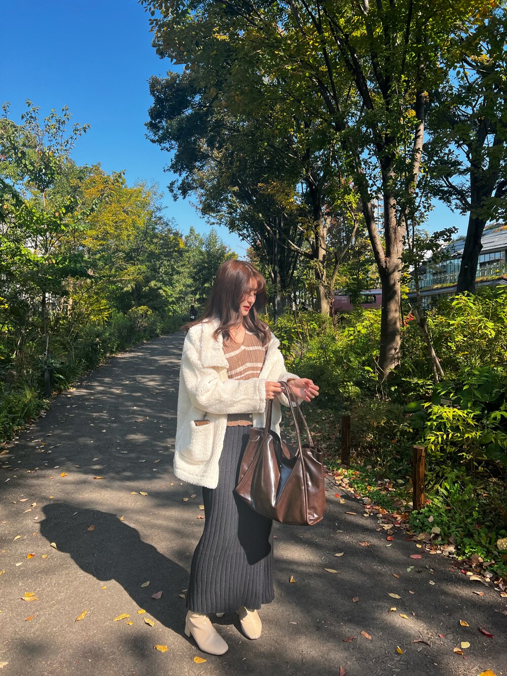 ホワイト系のムートンコート、ベージュ系のジャケット/アウター、ブラック系のスカートを着用したレディースの秋コーディネートの4枚目の写真