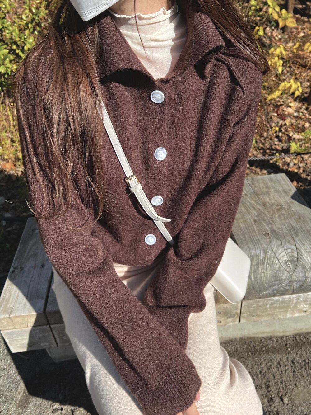 ブラウン系のニット/セーター、ホワイト系のショルダーバッグ、ホワイト系のスカートを着用したレディースの冬コーディネートの2枚目の写真