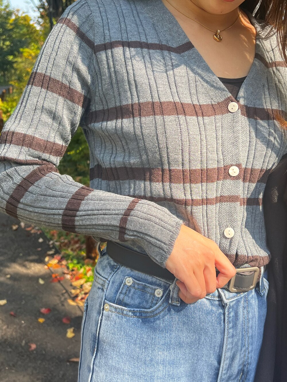 ブラック系のチェスターコート、ブラック系のハンドバッグ、グレー系のニット/セーターを着用したレディースの秋コーディネートの3枚目の写真