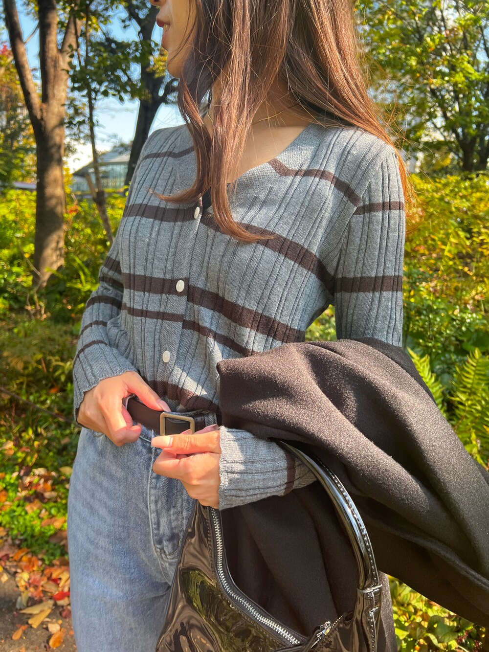 ブラック系のチェスターコート、ブラック系のハンドバッグ、グレー系のニット/セーターを着用したレディースの秋コーディネートの4枚目の写真