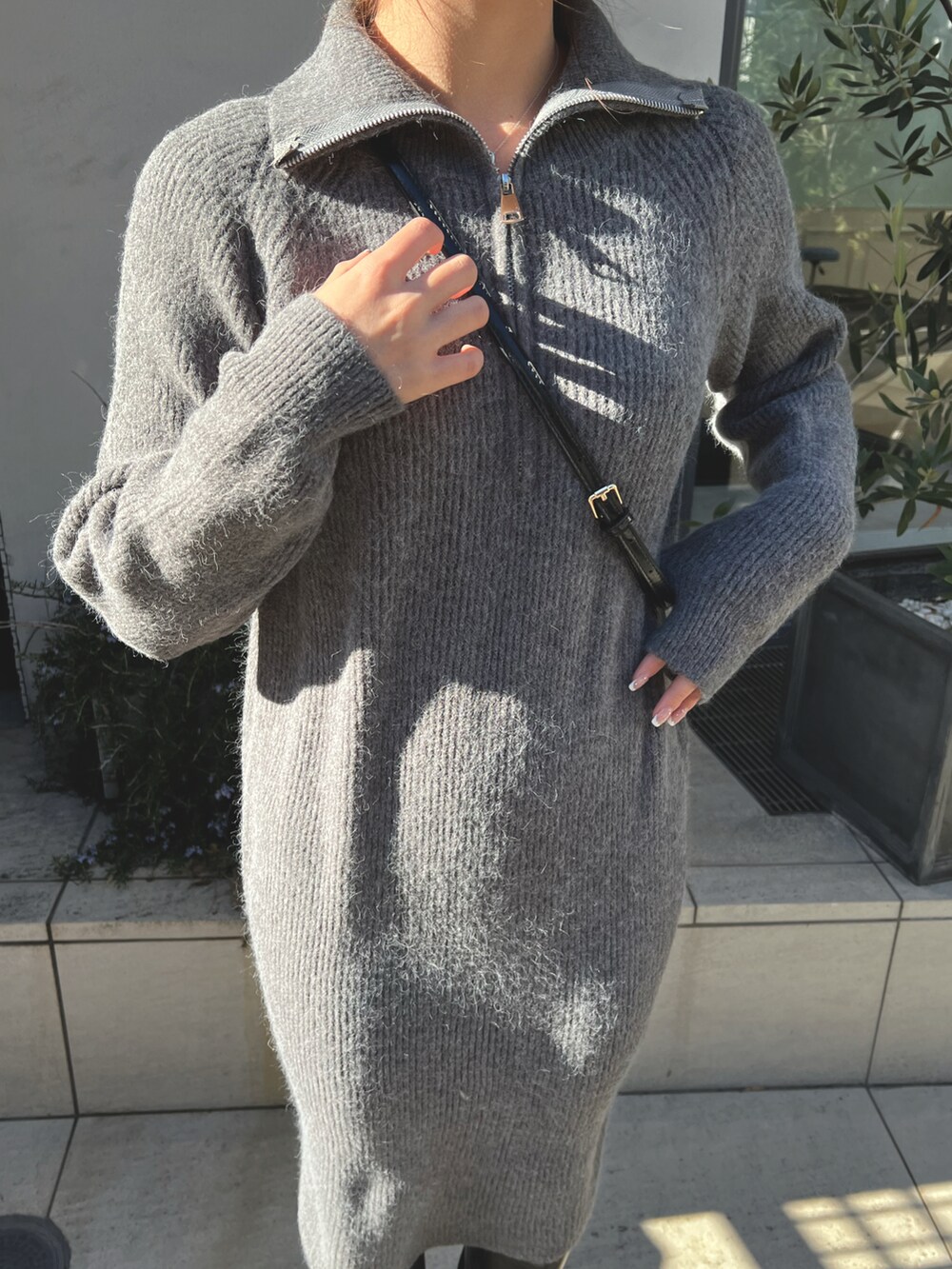 グレー系のワンピース、ブラック系のブーツを着用したレディースの冬コーディネートの2枚目の写真