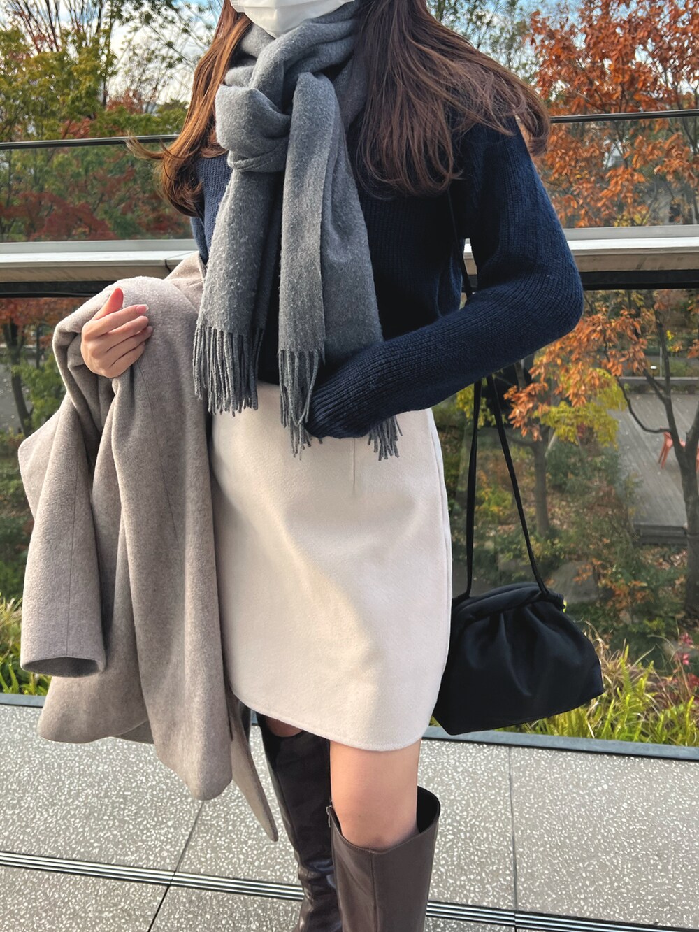 ブルー系のニット/セーター、ベージュ系のスカート、ブラック系のショルダーバッグを着用したレディースの冬コーディネートの2枚目の写真