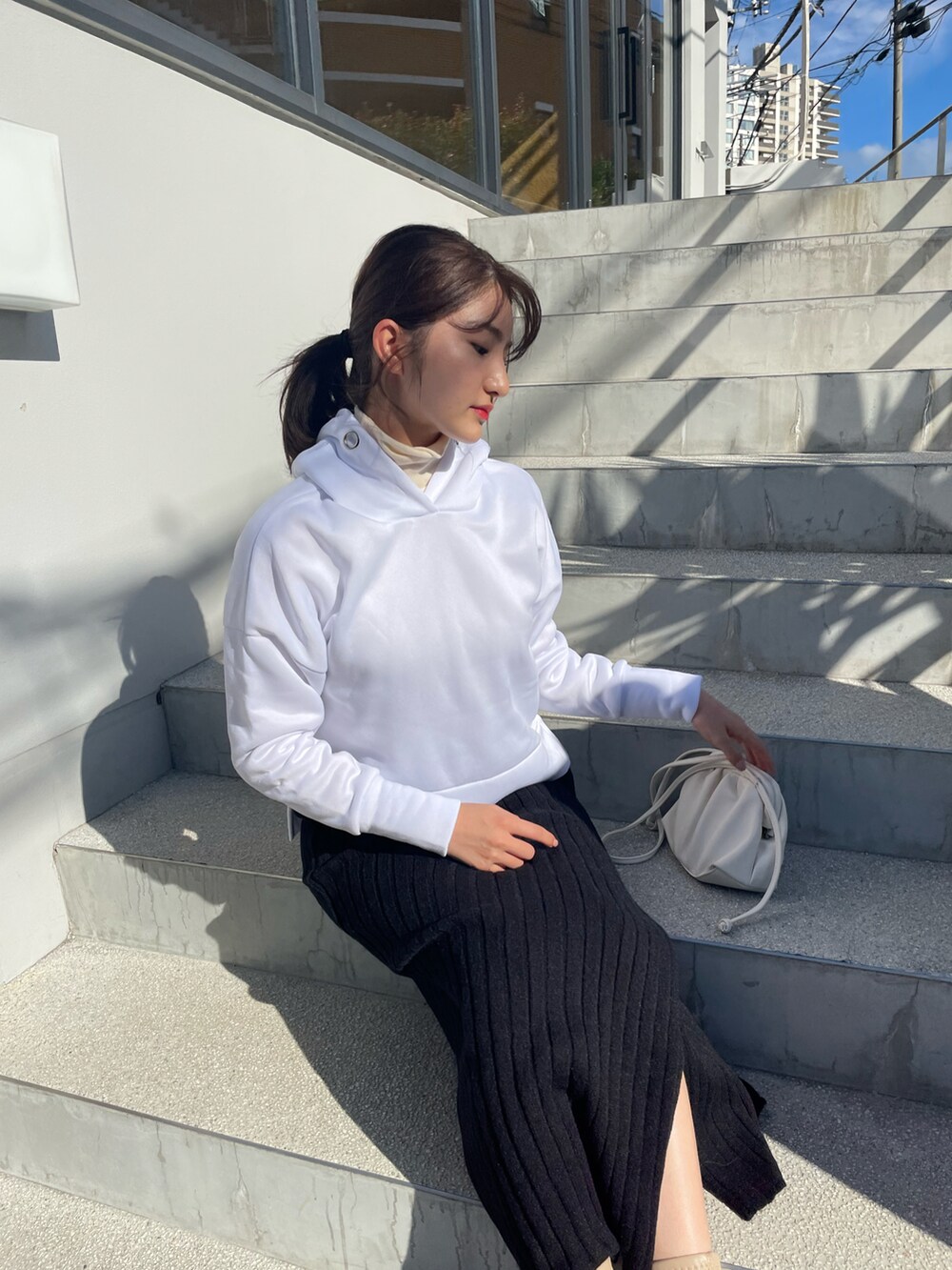 ブラック系のスカート、ホワイト系のショルダーバッグ、ホワイト系のニット/セーターを着用したレディースの秋コーディネートの2枚目の写真