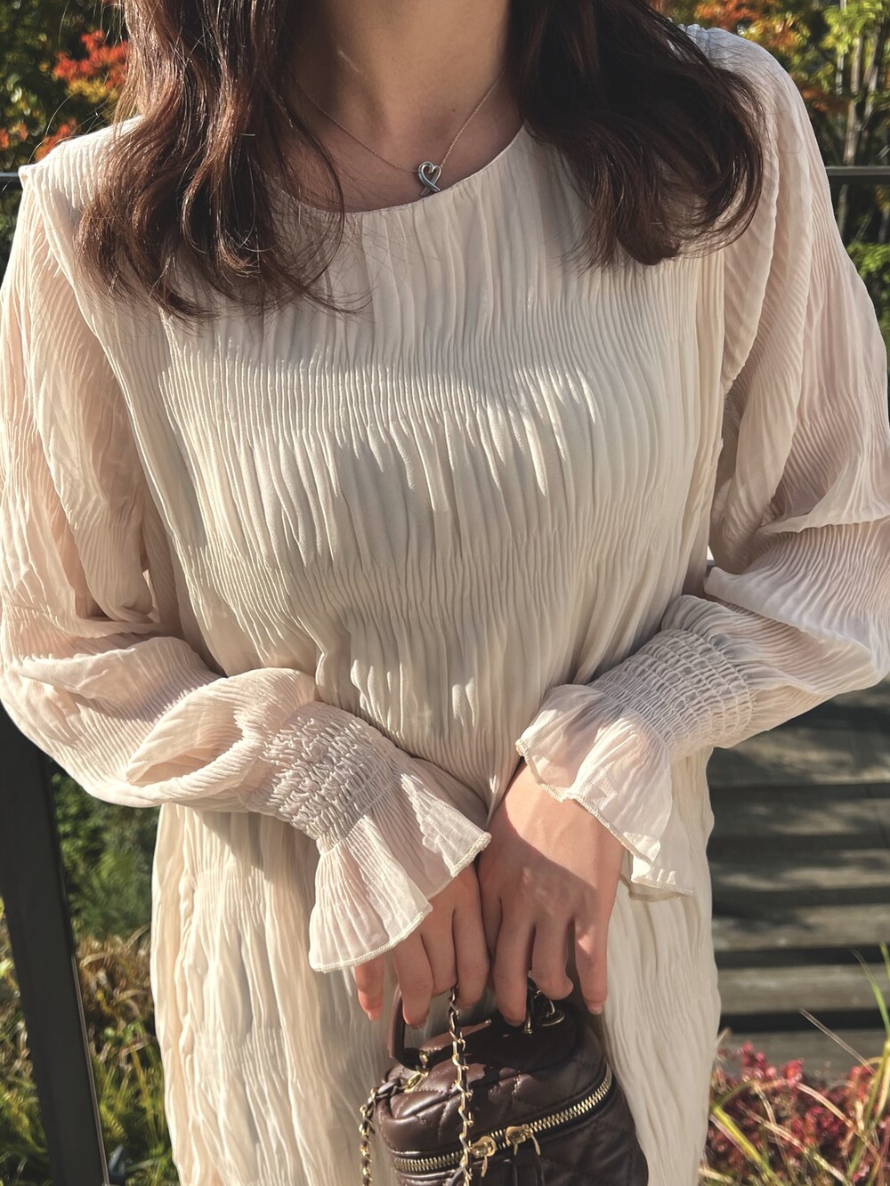 ホワイト系のワンピース、ブラウン系のショルダーバッグ、ベージュ系のブーツを着用したレディースの冬コーディネートの3枚目の写真