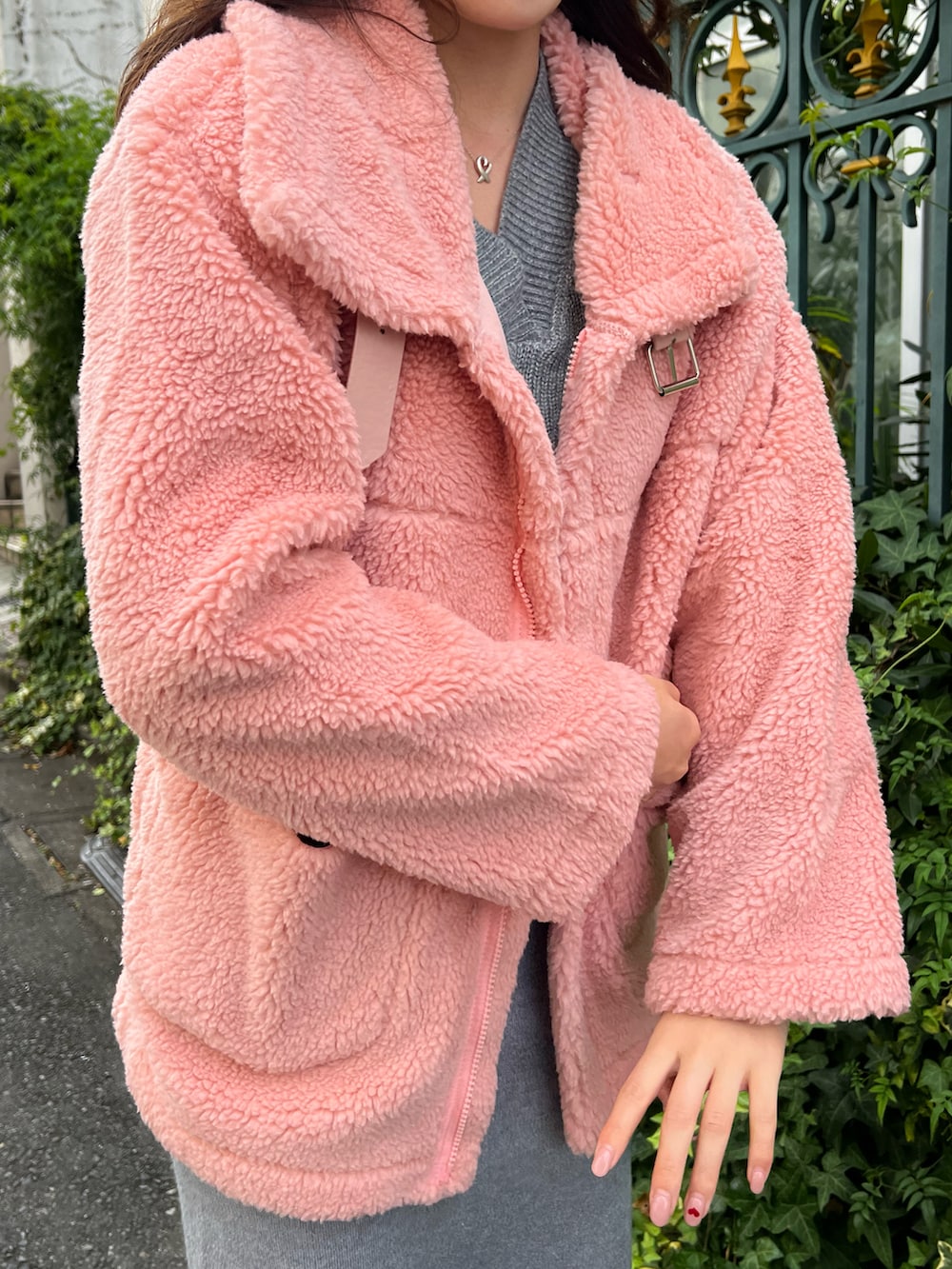 ピンク系のムートンコート、グレー系のニット/セーター、グレー系のスカートを着用したレディースの冬コーディネートの2枚目の写真