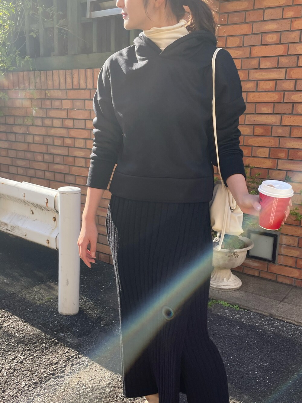 ブラック系のパーカー、ホワイト系のショルダーバッグ、ホワイト系のニット/セーターを着用したレディースの秋コーディネートの2枚目の写真