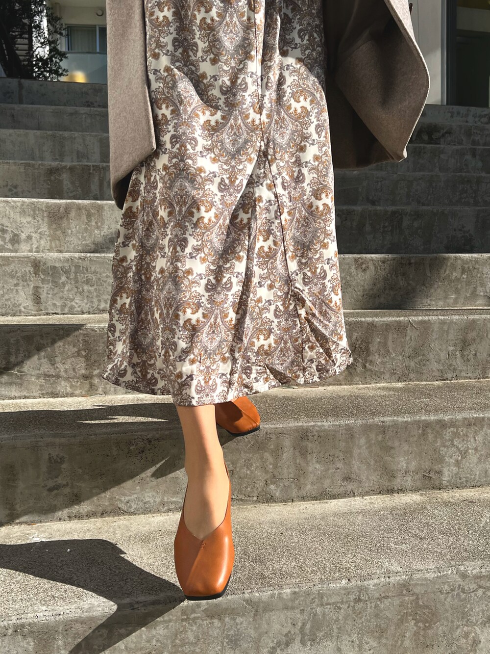 ブラウン系のパンプス、ホワイト系のスカートを着用したレディースの春コーディネートの2枚目の写真