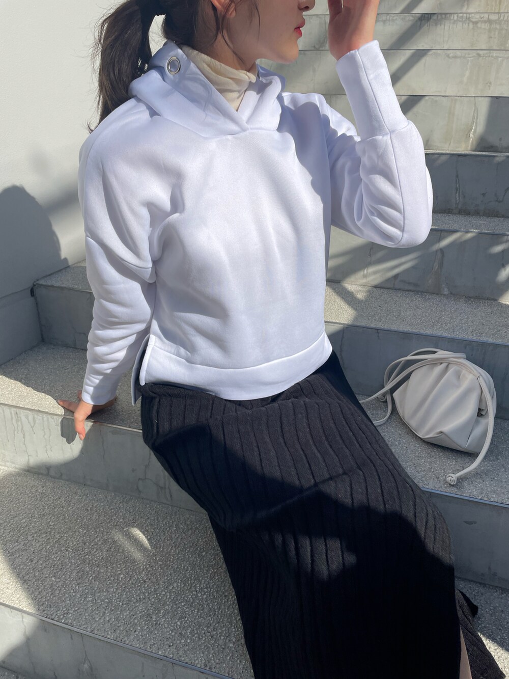 ブラック系のスカート、ホワイト系のショルダーバッグ、ホワイト系のニット/セーターを着用したレディースの秋コーディネートの3枚目の写真