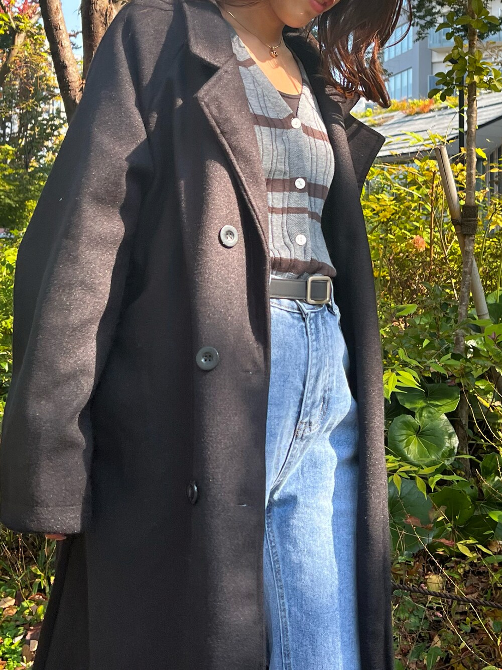 ブラック系のチェスターコート、ブラック系のハンドバッグ、グレー系のニット/セーターを着用したレディースの秋コーディネートの2枚目の写真