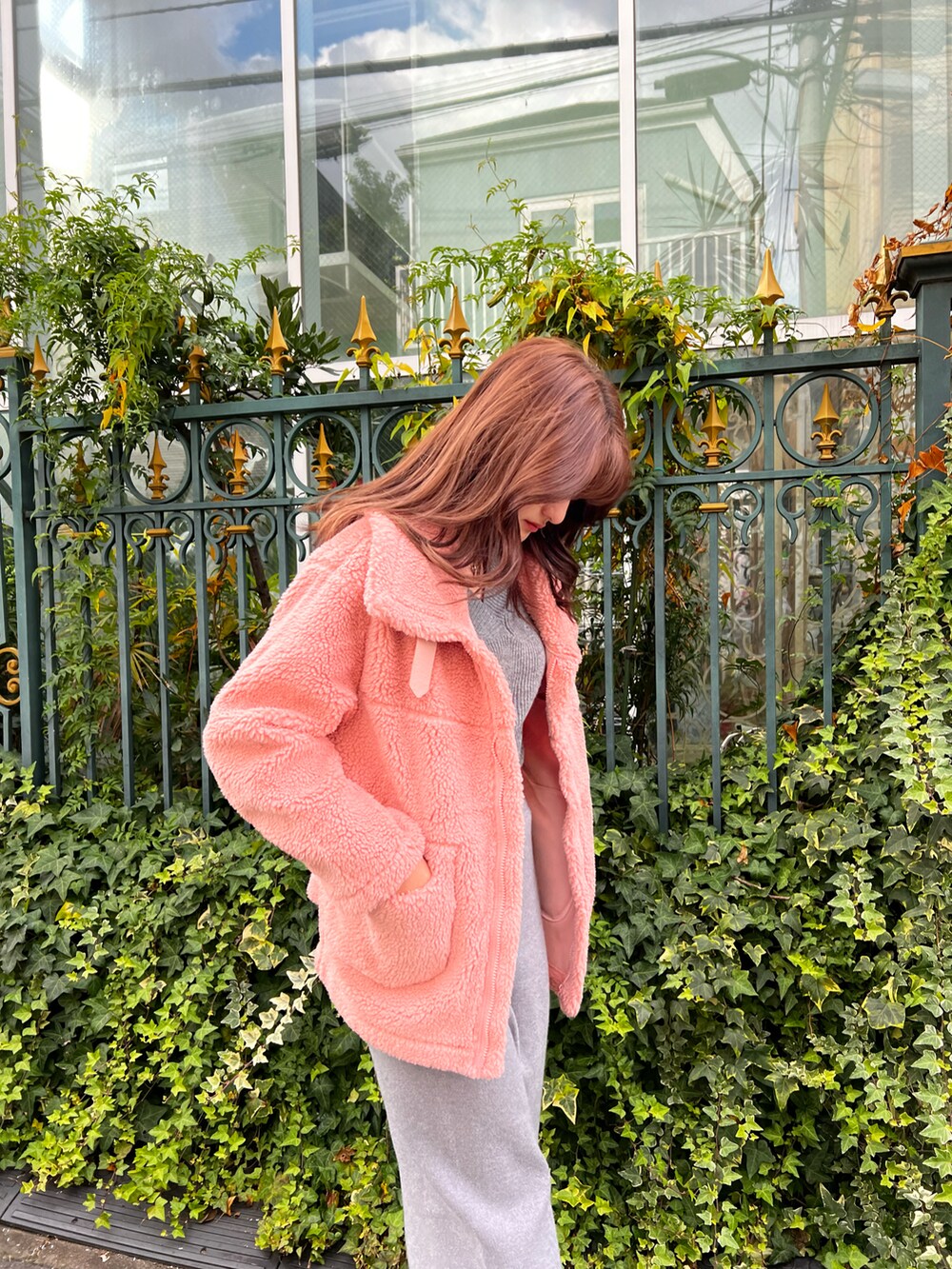 ピンク系のムートンコート、グレー系のニット/セーター、グレー系のスカートを着用したレディースの冬コーディネートの3枚目の写真