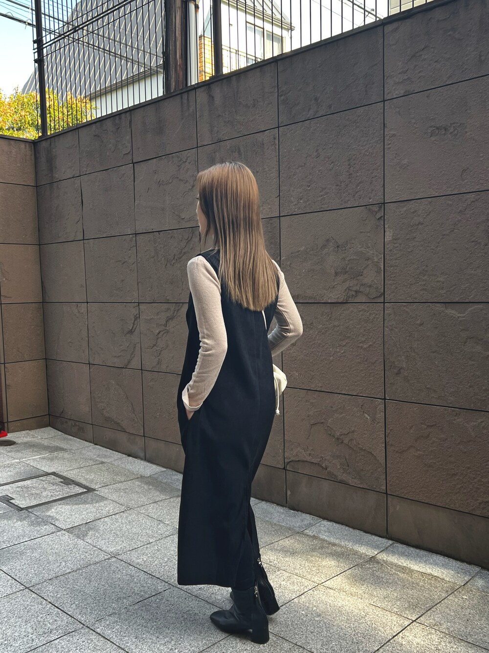 ブラック系のワンピース、ホワイト系のショルダーバッグ、ベージュ系のニット/セーターを着用したレディースの冬コーディネートの2枚目の写真