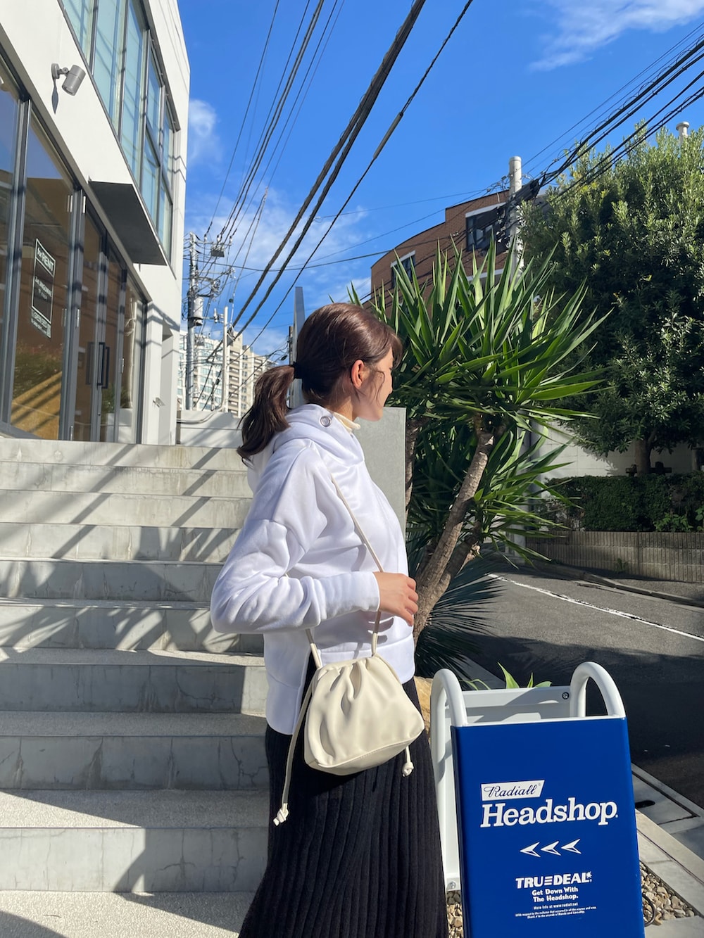 ブラック系のスカート、ホワイト系のショルダーバッグ、ホワイト系のニット/セーターを着用したレディースの秋コーディネートの4枚目の写真