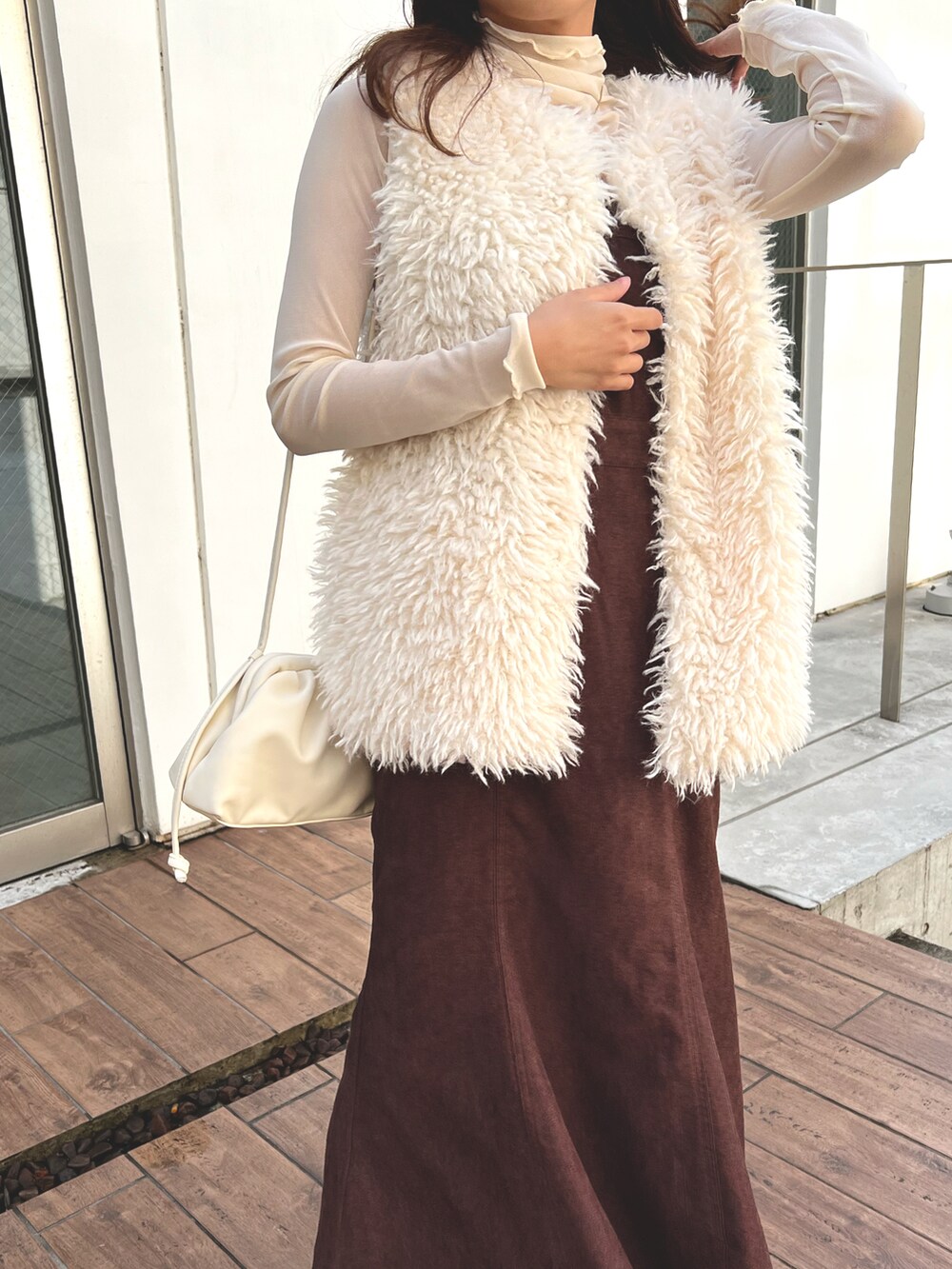 ホワイト系のベスト、ベージュ系のベストを着用したレディースの春コーディネートの2枚目の写真