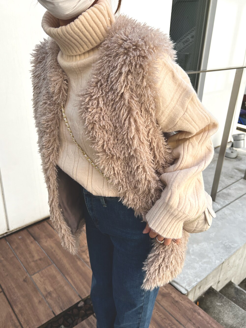 ベージュ系のベスト、ホワイト系のショルダーバッグを着用したレディースの冬コーディネートの2枚目の写真